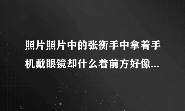 照片照片中的张衡手中拿着手机戴眼镜却什么着前方好像那里有比手机更吸引他的？